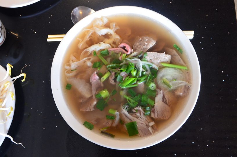 Beef pho in a white bowl.
