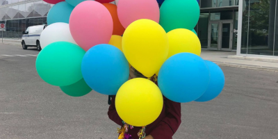 A girl holds balloons outside of E5.