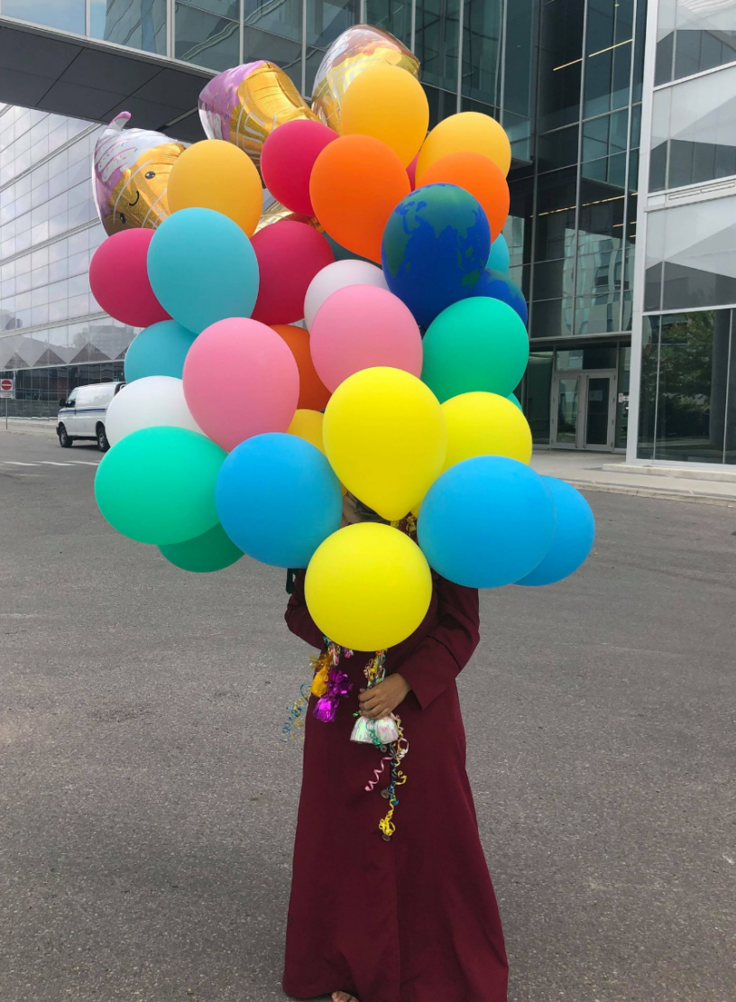 A girl holds balloons outside of E5.